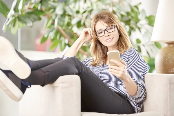Frau sitzt zu Hause und schreibt SMS. — Stockfoto
