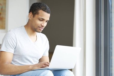 Genç adam laptopunu kullanıyor.
