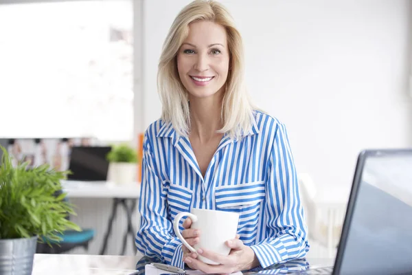 Frau trinkt Tee im Büro. — Stockfoto