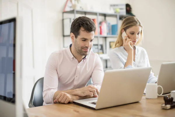 Compañeros de trabajo sentados en el escritorio — Foto de Stock