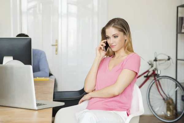 Businesswoman using laptop and making call — Stock Photo, Image