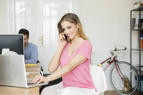 Zakenvrouw met behulp van laptop en bellen — Stockfoto