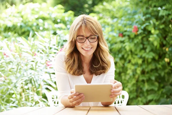 Femme souriante utilisant une tablette numérique — Photo