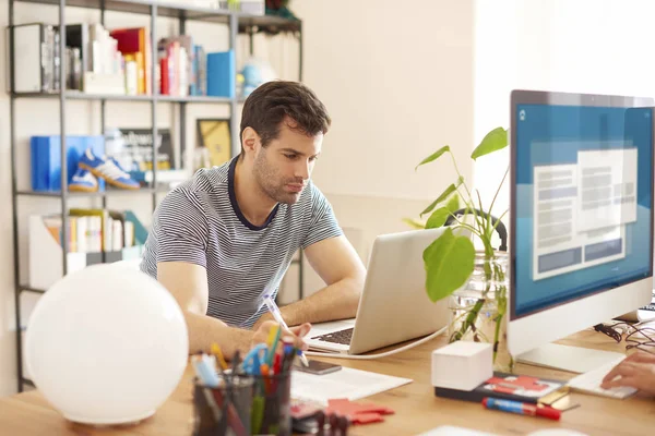 Hombre sentado en el escritorio delante de la computadora portátil — Foto de Stock