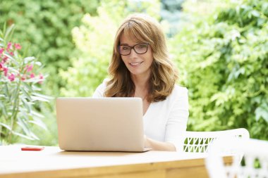 Otururken dizüstü bilgisayar kullanan kadın