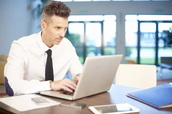 Businessman sitting with laptop at office — Stock Photo, Image