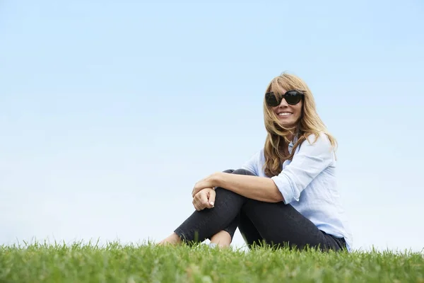 Žena sedící na trávě — Stock fotografie