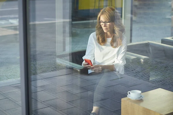 Woman sitting behind a glass window — Stock Photo, Image