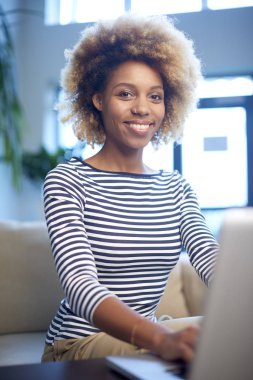 Dizüstü bilgisayarıyla çalışan genç bir kadın. 