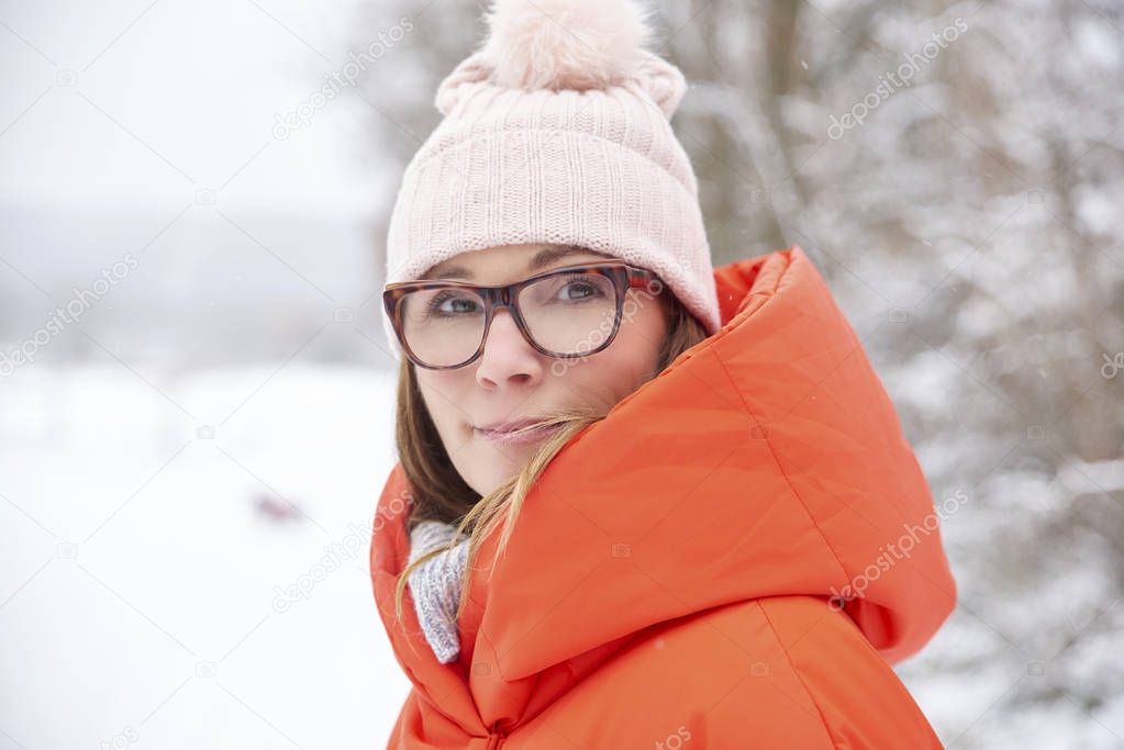 Close-up portrait of happy mature woman standing outside at snowy landscape and enjoy winter season. 