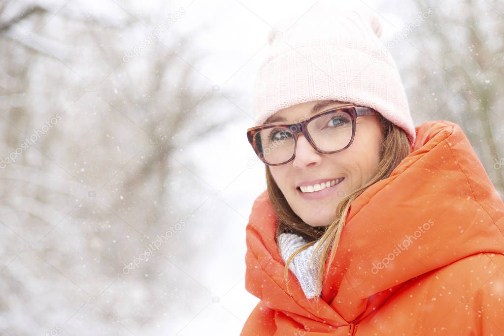 Close-up portrait shot a happy woman wearing hat and warm coat while standing outdoors
