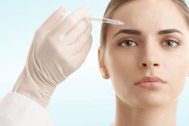 Botox tedavisi alma çekici bir genç kadın portresi. Açık mavi renkli izole. 