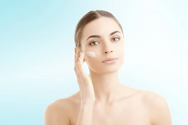 Foto Estudio Una Hermosa Mujer Joven Aplicando Crema Hidratante Cara — Foto de Stock