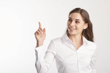 Beyaz gömlek giymiş ve kopya alanı onun parmak ile işaret ederken ararken genç kadın portresi. İzole beyaz arka plan. 