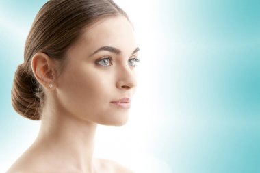 Yakın çekim studio karşı izole ışık mavi bakcground ayakta ve uzak arıyorum güzel genç kadını vurdu.