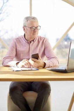 Ofis büro dizüstü bilgisayar ve çalışma önünde, çalışırken onun cep telefonuyla düşünme üst düzey işadamı portresi.