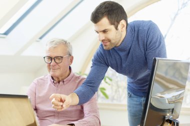 Ofis Masası onun genç asistanı iş adamı onun yanındaduruyor ve yeni proje hakkında danışmanlık bilgisayar önünde oturan üst düzey iş adamı. Ofiste takım çalışması. 