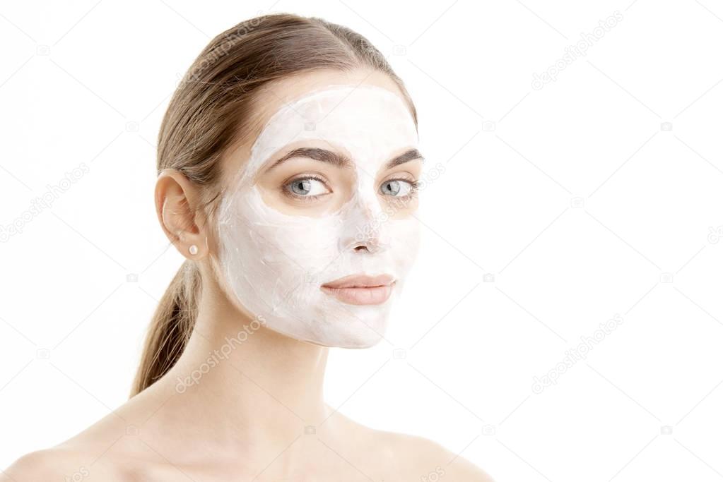 Close-up shot of a beautiful young woman wearing a face mask. Isolated on white background.