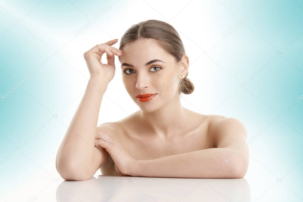 Studio shot of a young woman with perfect skin posing against at isolated light blue background.
