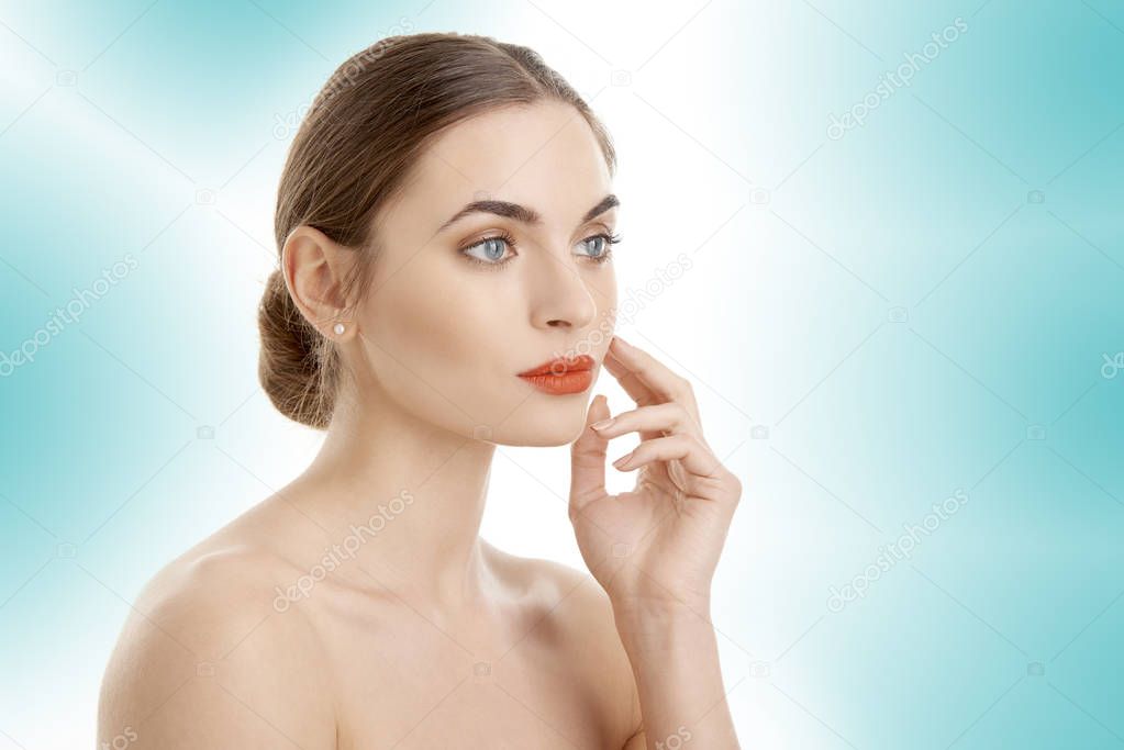 Half-faced profile of a beautiful young woman with perfect skin. Isolated on light blue background. 