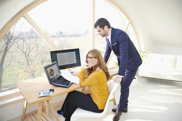 Lächelnde Reife Geschäftsfrau Die Schreibtisch Sitzt Während Ihr Junger Kollege — Stockfoto