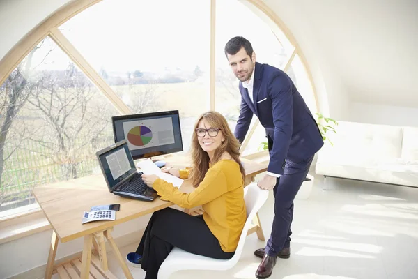 Lächelnde Reife Geschäftsfrau Die Schreibtisch Sitzt Während Ihr Junger Kollege — Stockfoto