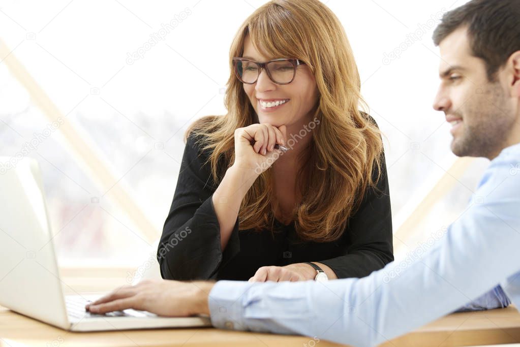 Young financial assistant businessman sitting in front of laptop and presenting his business plan to the executive businesswoman. Group of business people working together at the office. 