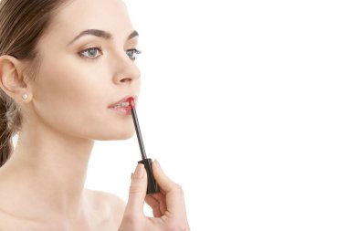 İzole edilmiş beyaz arka planda duran, uygulamalı pembe ruj süren genç bir kadın.. 