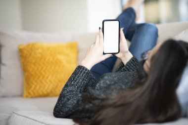 Evdeki koltukta dinlenirken cep telefonu ve kısa mesaj kullanmanın arka plan görüntüsü. 