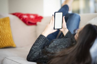 Evdeki koltukta dinlenirken cep telefonu ve kısa mesaj kullanmanın arka plan görüntüsü. 