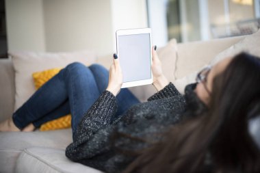 Evdeki kanepede dinlenirken dijital tablet kullanmanın arka plan görüntüsü. 
