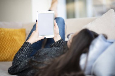 Evdeki kanepede dinlenirken dijital tablet kullanmanın arka plan görüntüsü. 