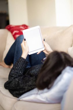 Arka planda, elinde boş ekranla elinde dijital tablet olan bir kadın var..