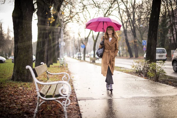 雨天在街上散步时拿着雨伞的成熟女子的全照 — 图库照片