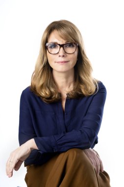 Çekici orta yaşlı bir iş kadınının, izole edilmiş beyaz arka planda otururken kameraya bakıp gülümsemesinin portresi.. 