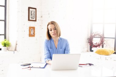 Çekici, olgun bir iş kadınının ofis masasında defterinin arkasında otururken kağıt işleriyle uğraşması..