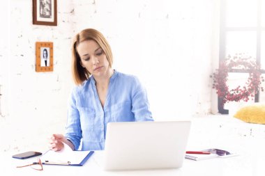 Çekici, olgun bir iş kadınının ofis masasında defterinin arkasında otururken kağıt işleriyle uğraşması..
