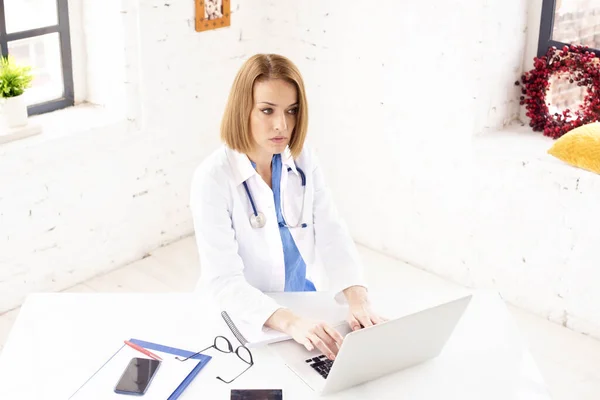 彼女のラップトップと仕事の後ろに座っている中年女性医師のショット — ストック写真
