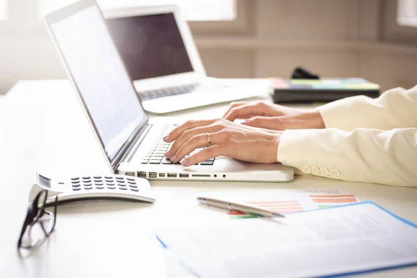 オフィスの机でノートパソコンで仕事をしながら金融ビジネスの女性の手のクローズアップ — ストック写真