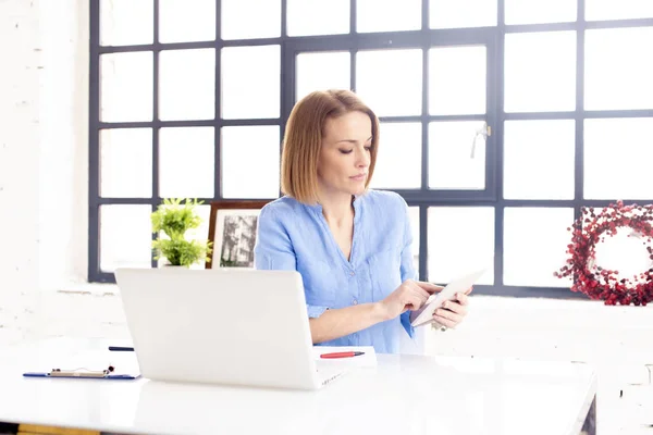オフィスの机で彼女のラップトップの後ろに座っている間 デジタルタブレットを使用して魅力的なビジネスマンのショットとオンラインで働く — ストック写真