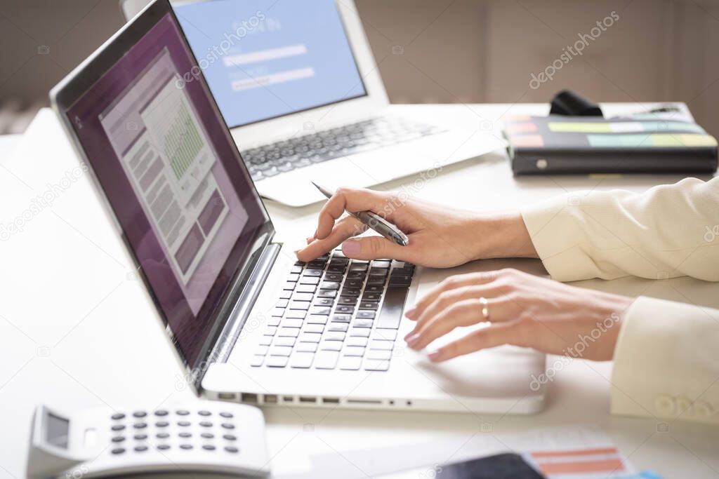 Close-up of businesswoman's hands while working on her laptop at office desk. 