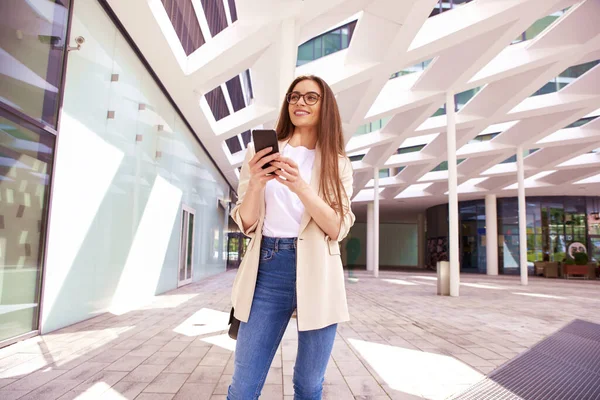 Çekici Genç Bir Kadının Ofis Binasının Önünde Dikilip Mesajlaşması — Stok fotoğraf