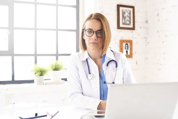 Kadın Doktor Doktorun Ofisinde Dizüstü Bilgisayarının Arkasında Oturuyor — Stok fotoğraf