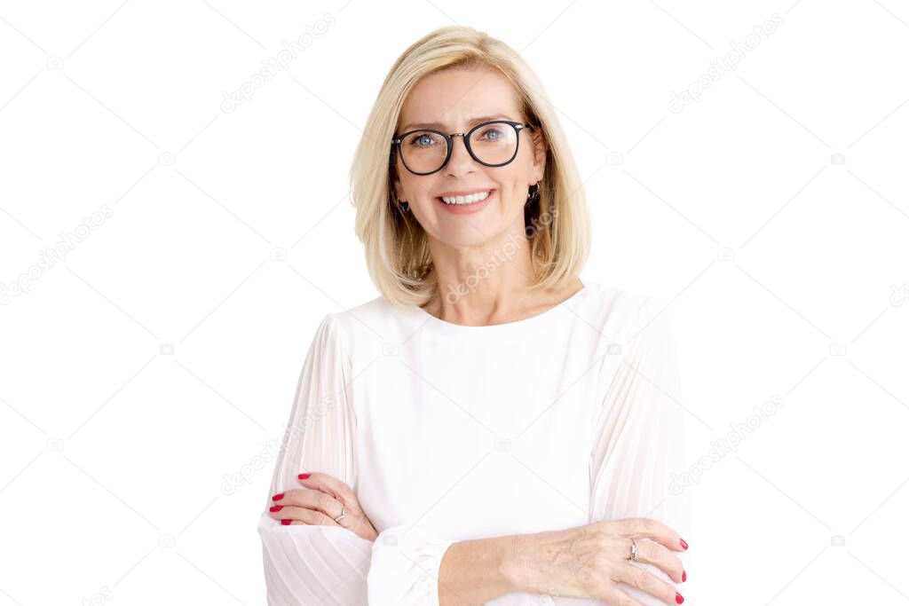 Close-up portrait shot of beautiful blond senior woman standing with arms crossed at isolated white backkground.