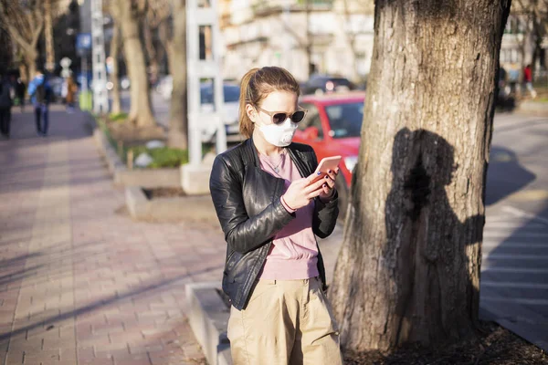 在科罗纳韦病毒爆发期间 一名戴口罩的年轻女子因健康保护而被枪击身亡 信心十足的女人在街上散步时发短信 — 图库照片