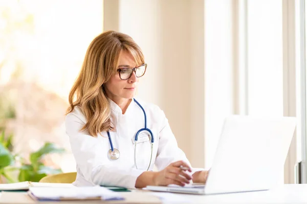 Portraitaufnahme Einer Ärztin Mittleren Alters Die Schreibtisch Sitzt Und Arbeitet — Stockfoto