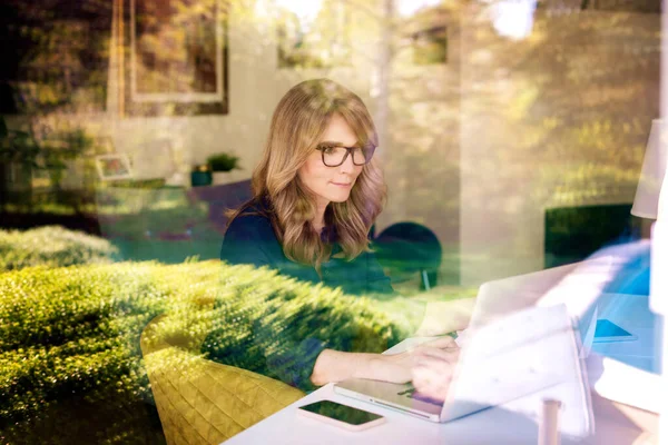 Een Glimlachende Vrouw Van Middelbare Leeftijd Die Achter Haar Laptop — Stockfoto