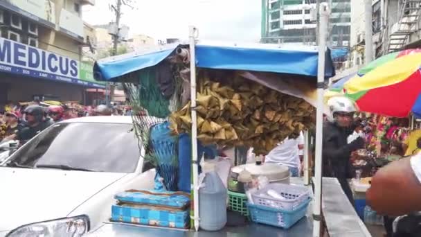 Straatverkoper op een driewieler verkoopt pakjes rijst verpakt in bladeren bij Sinulog. — Stockvideo