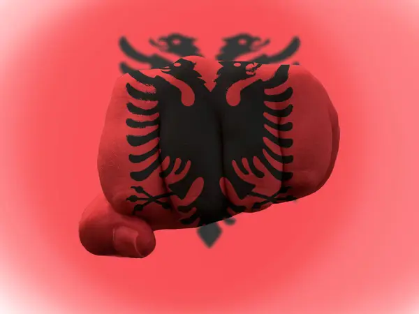 Прапор Албанії зображений на людському кулаку, що представляє владу. — стокове фото