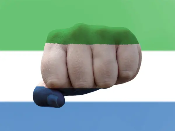 Прапор Сьєрра-Леоне зображений на людському кулаку, що представляє владу. — стокове фото